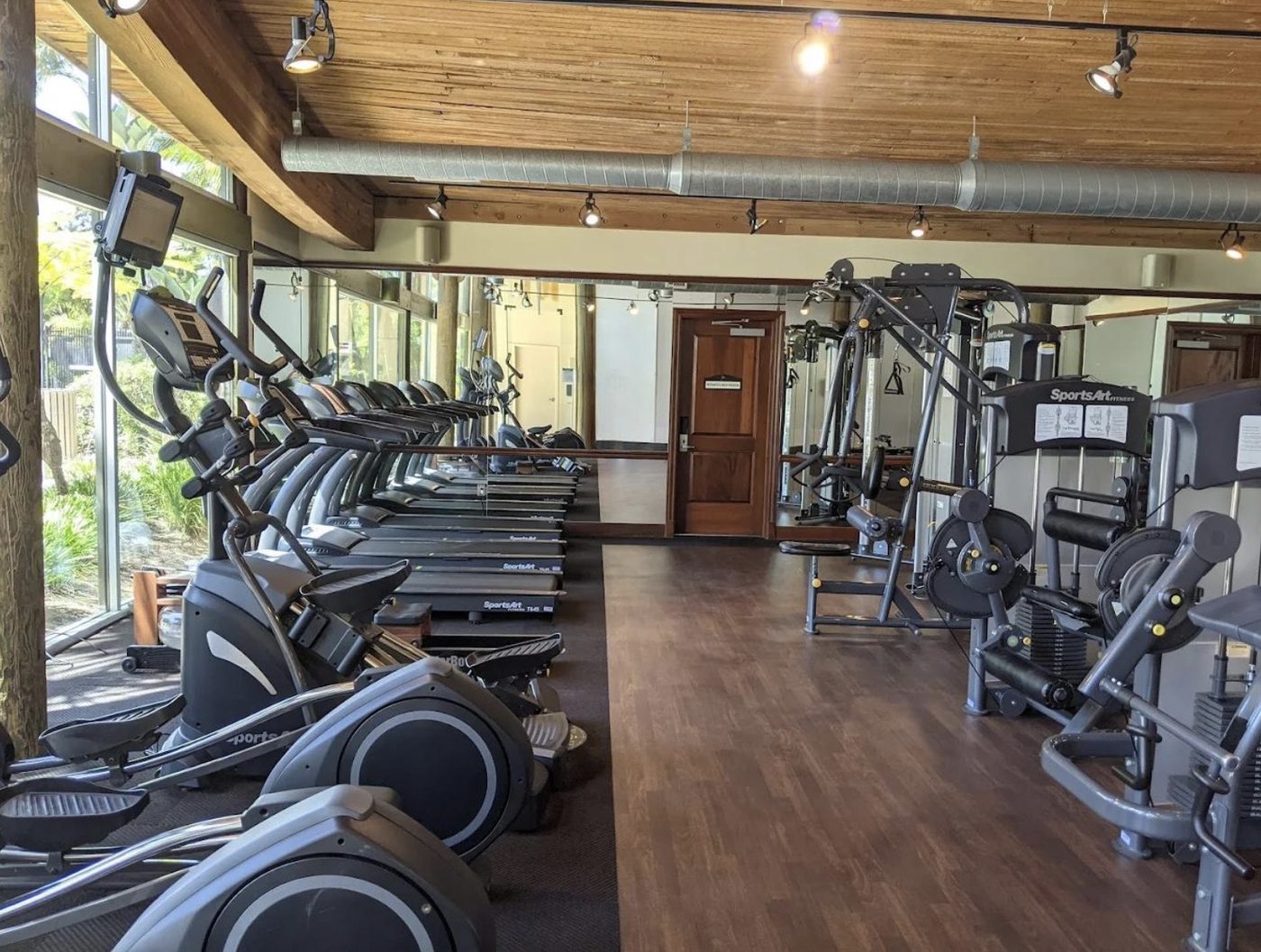 Apartment amenity fitness room with cardio equipment along a window wall