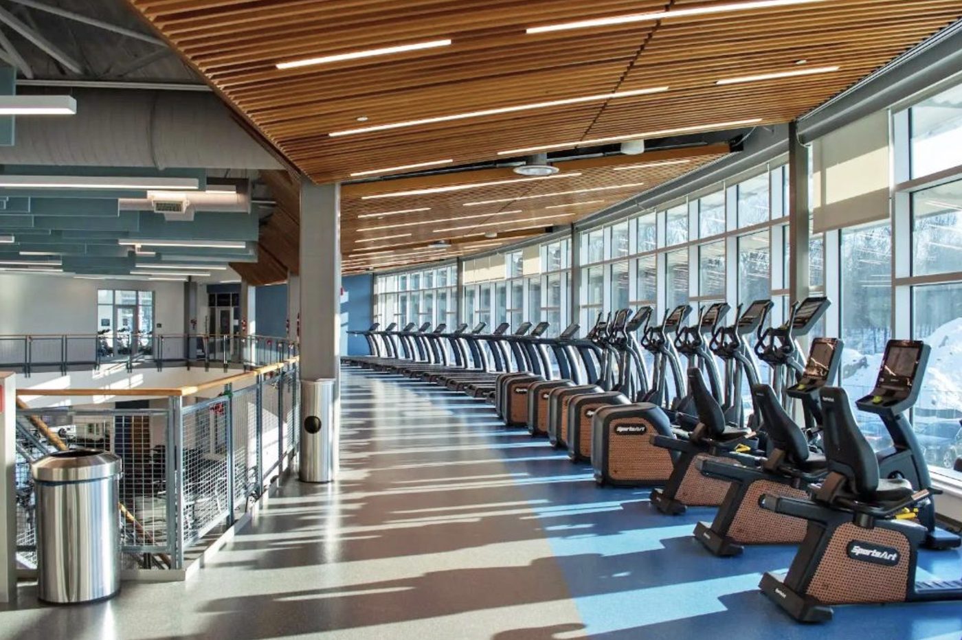 Commercial fitness facility with a row of cardio equipment along a window wall