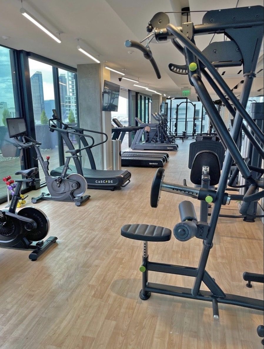 Amenity fitness room with cardio and strength equipment overlooking a city view