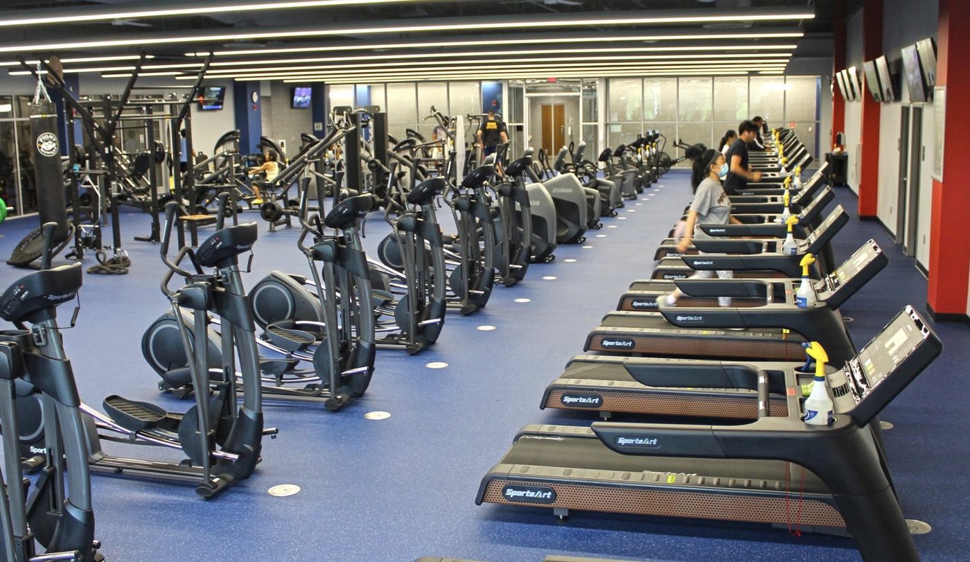 Large commercial fitness floor with rows of cardio equipment