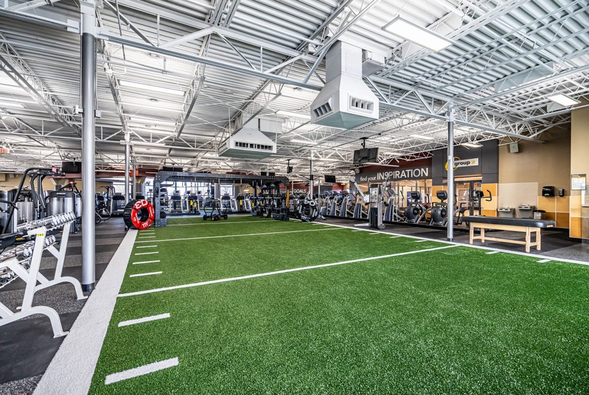 Commercial gym training floor with synthetic turf sprint lanes and yard-line markings