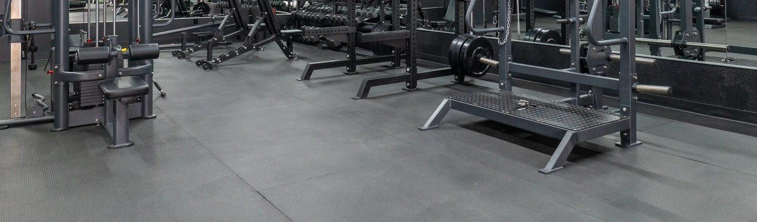 Grey rubber studio flooring with strength equipment along a wall